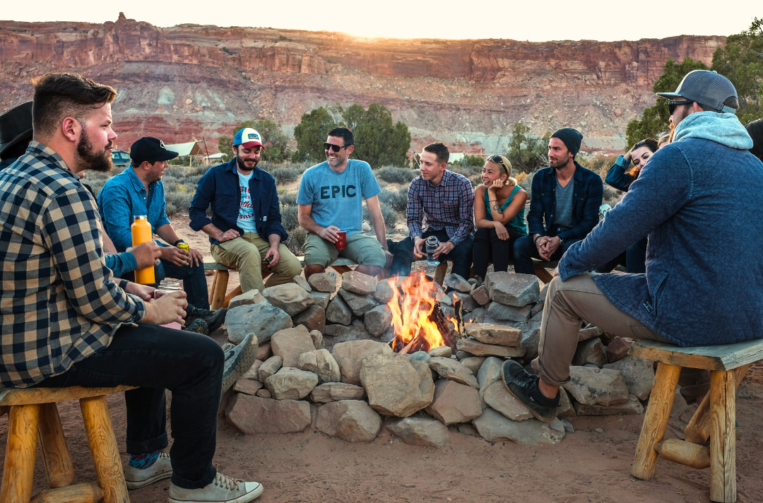 Photo shows a group of men around a campfire.