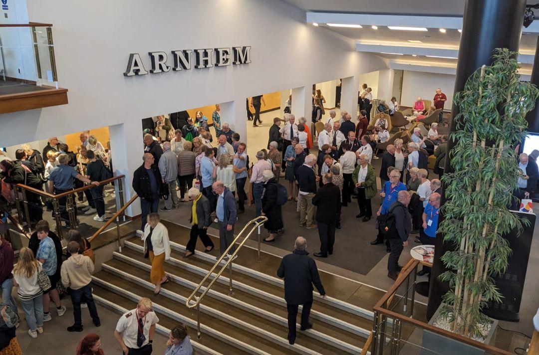 A photo of a large crowd in a concert hall foyer