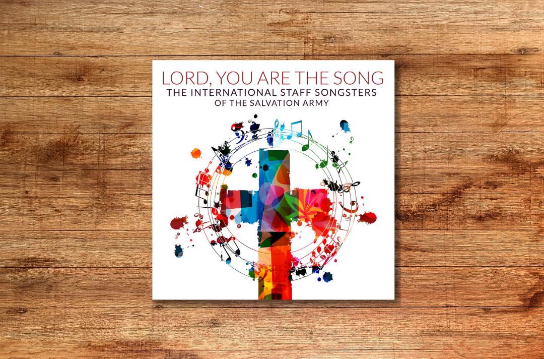 A graphic shows the cover of Lord, You Are the Song against a wooden background.