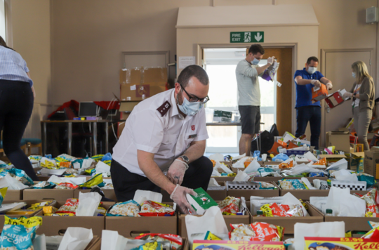 Salvationist wearing a face masks and preparing food parcels
