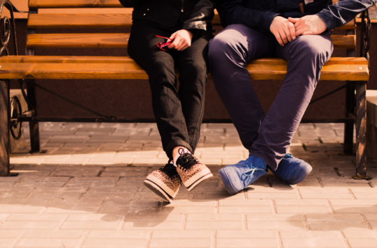 Two teenagers talking on a bench