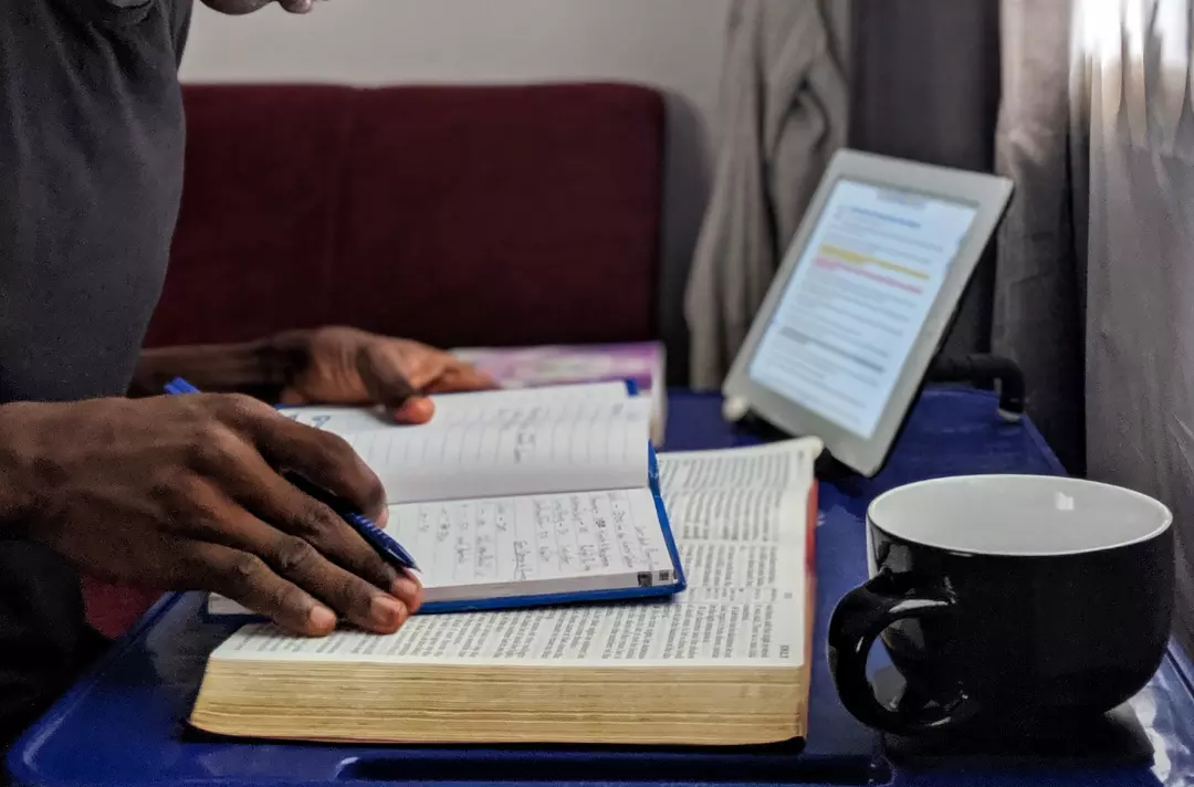 Someone studying the Bible with a notepad and computer