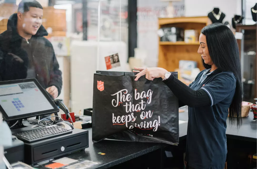 A Salvation Army charity shop volunteer serving a customer
