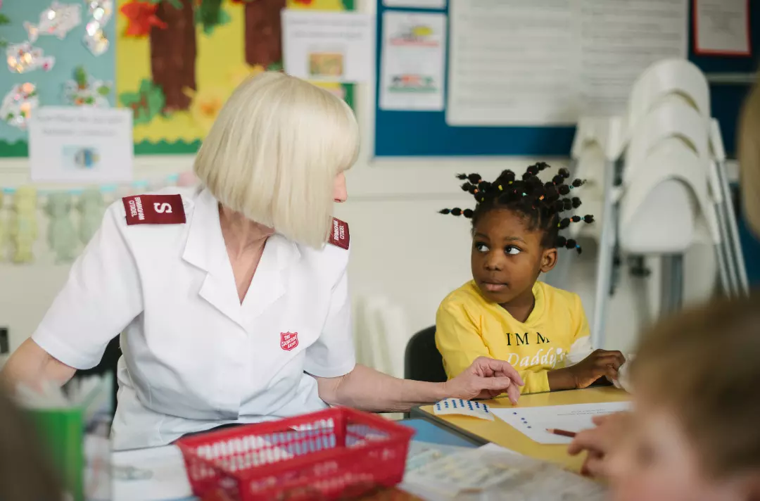A Salvation Army children's working helping a child with craft