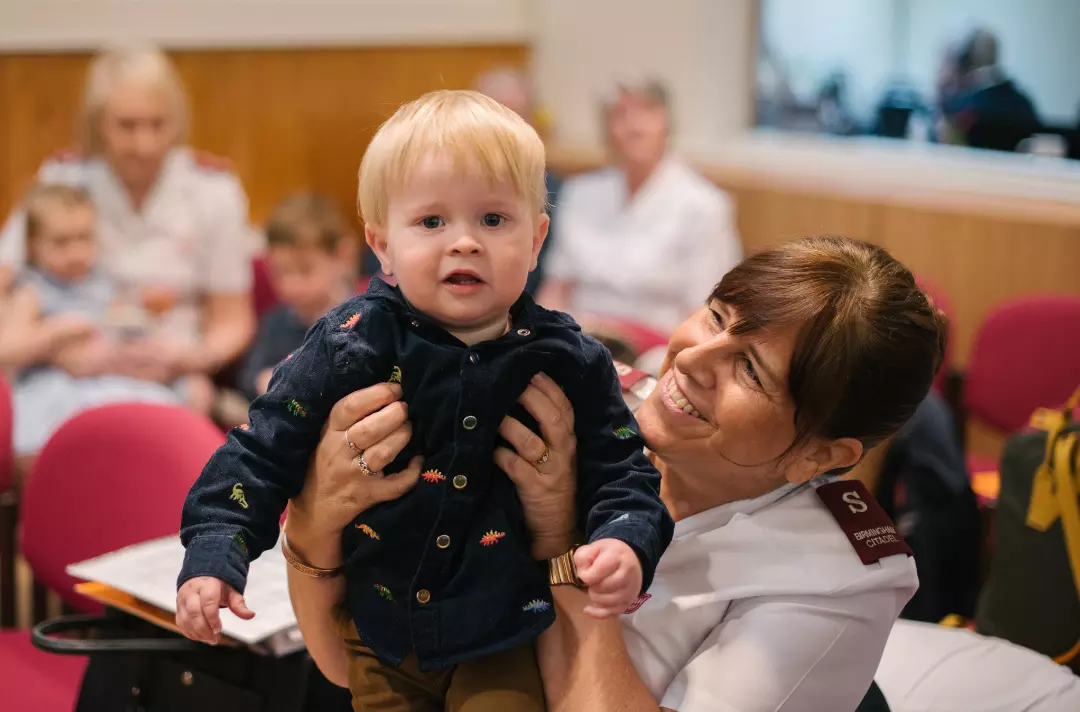 A Salvationist holding a toddler