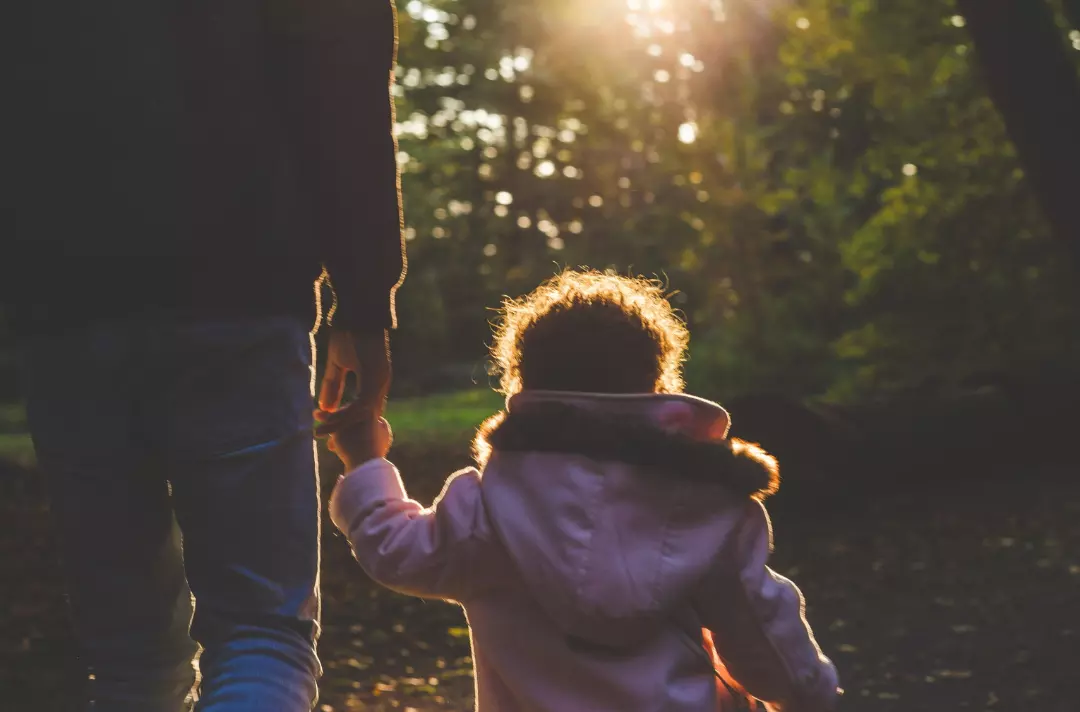 A photo of a father holding their child's hand