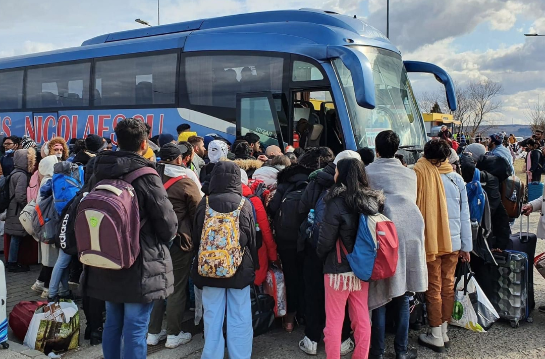Refugees with suitcases boarding a bus