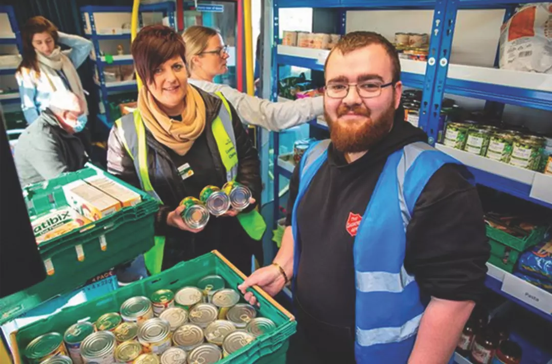 Staff holding tins of food inside the Sheppey Support Bus