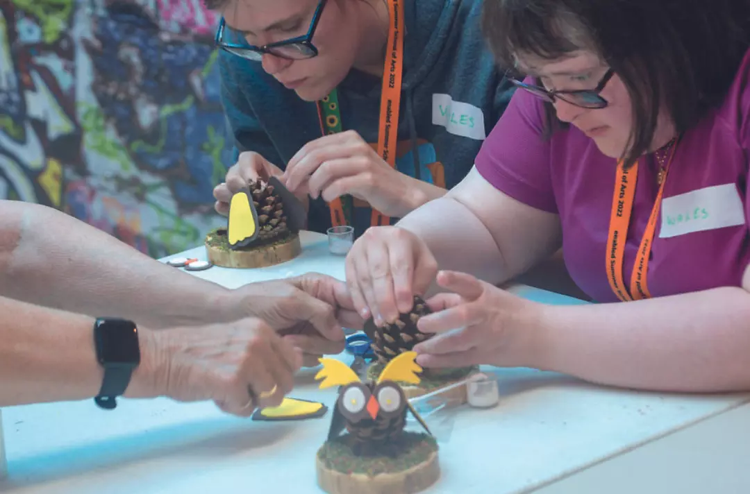 People making owl ornaments made from pine cones