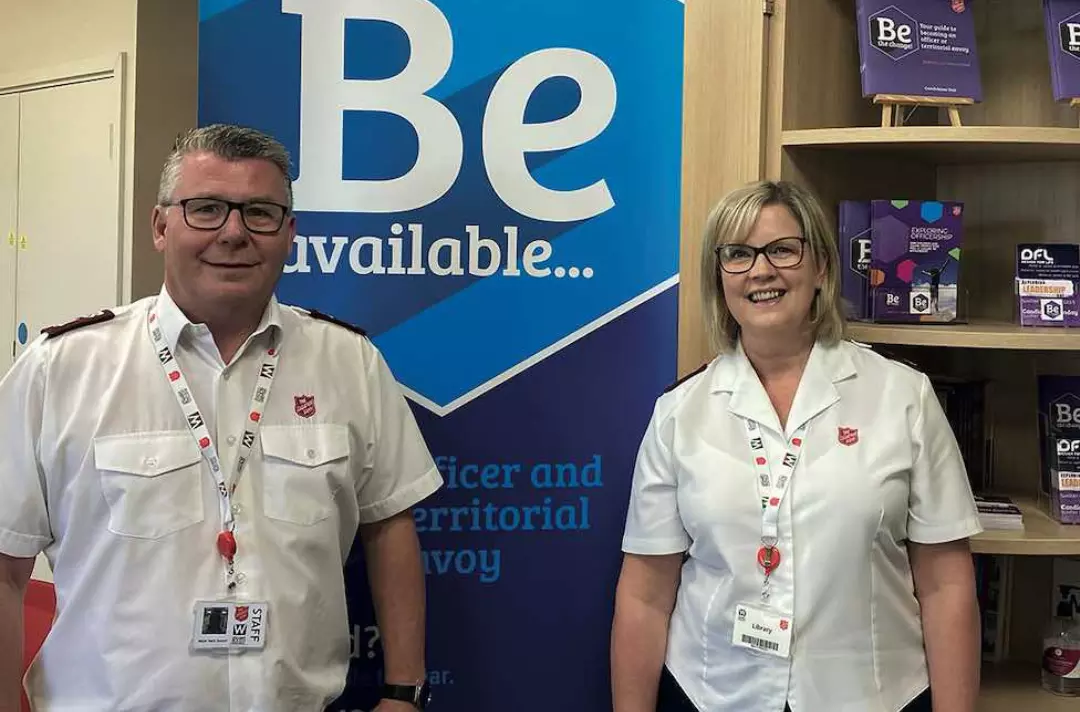 Mark and Andrea Sawyer standing next to a pop-up banner that reads 'Be available'
