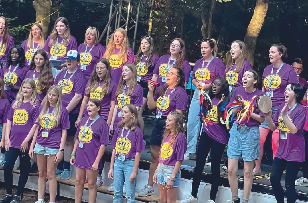 A youth choir singing with people playing percussion