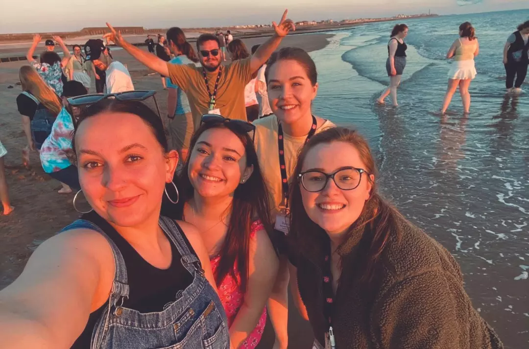 A group of teenagers and young adults paddling in the sea at sunset