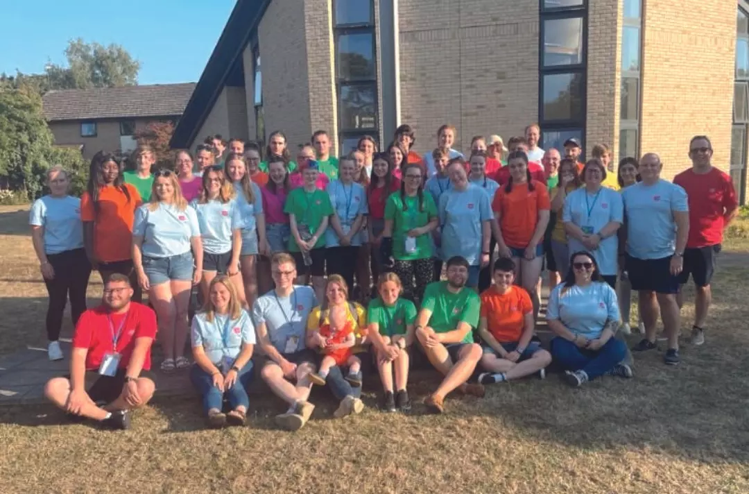 A group of teenagers and adults wearing brightly coloured Salvation Army polo shirts