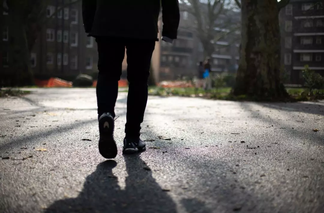 Someone walking through a housing estate and casting a shadow