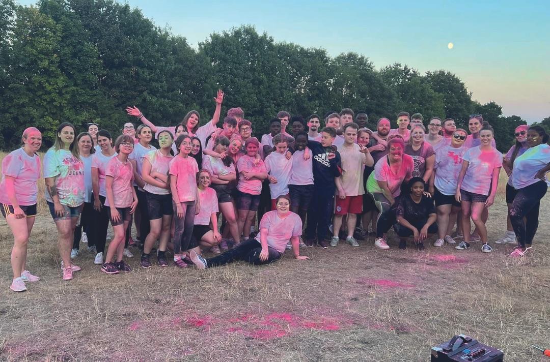 A group of teenagers and adults covered in powered paint standing in a field