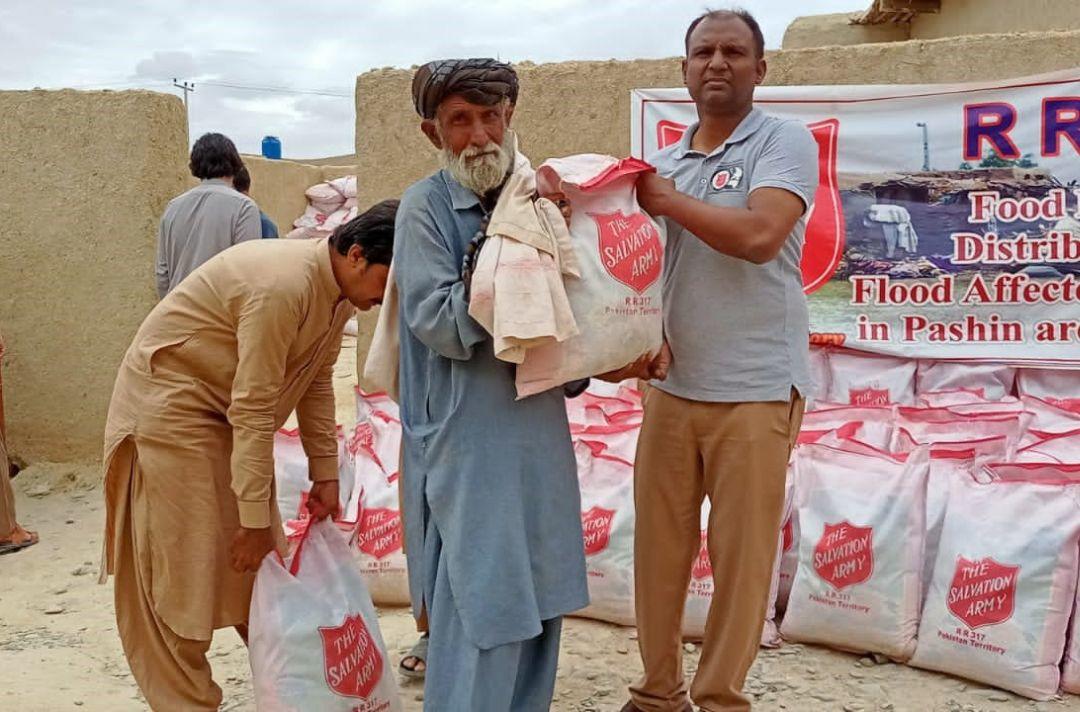 People in Pakistan holding bags of food with The Salvation Army's red shield on them