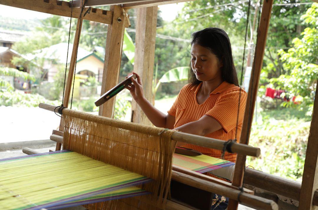 A woman using a weaving loom