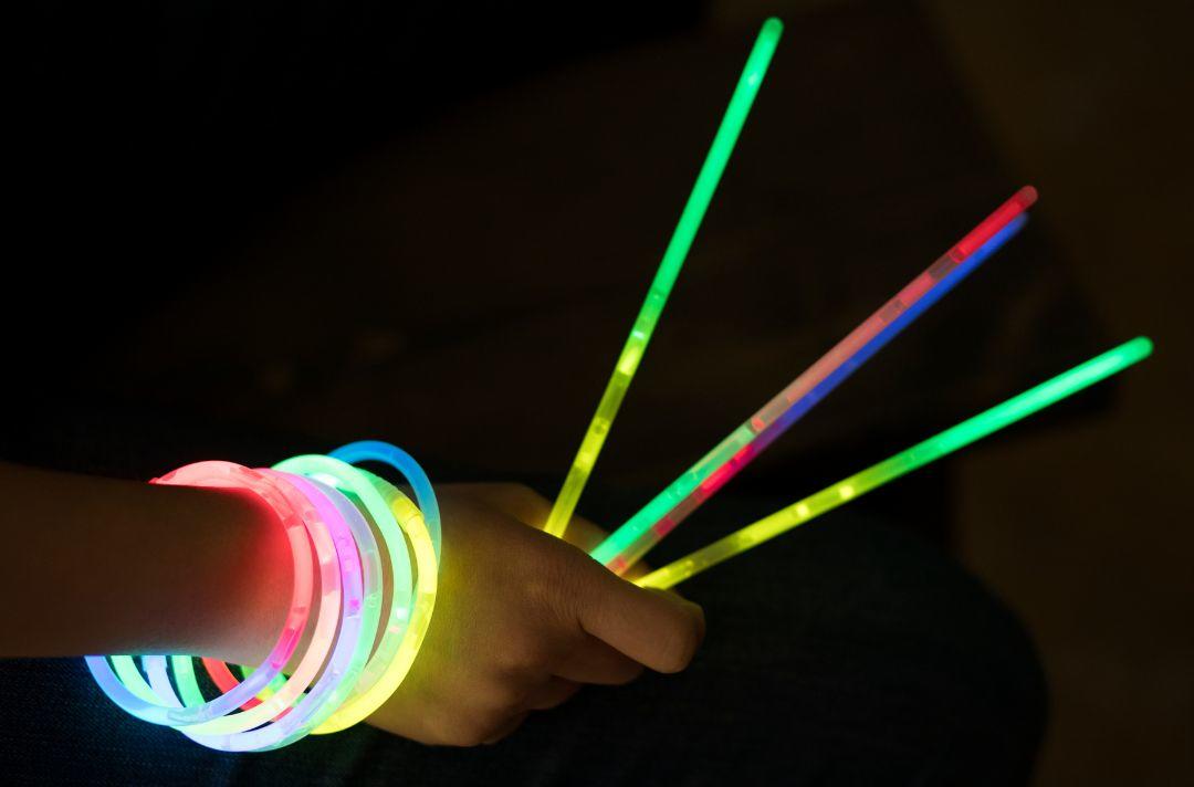 A photo of someone holding glow sticks and wearing glow stick bangles