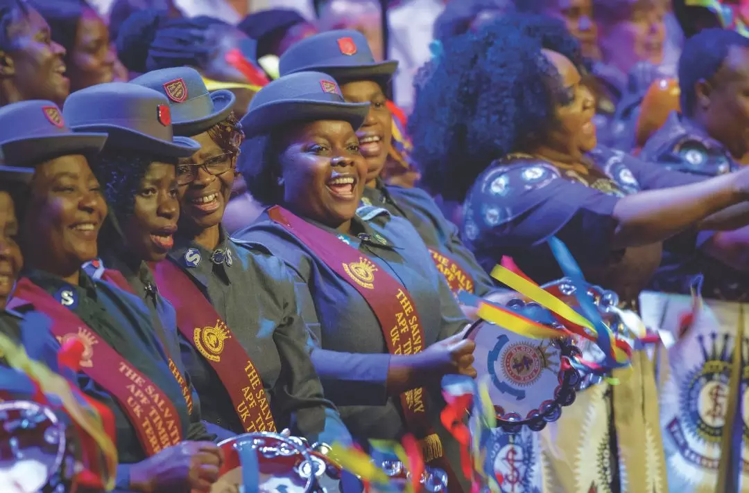 A group of people wearing grey Salvation Army uniform and playing timbrels