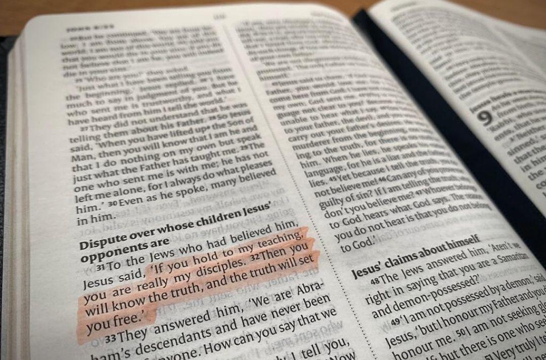 A photo of the Bible open at John 8 with verses 31-32 highlighted in orange