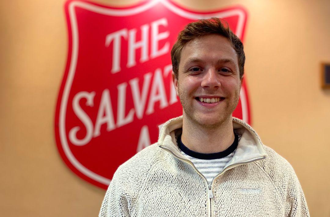 A photo of Sam Davidson in front of a Salvation Army red shield