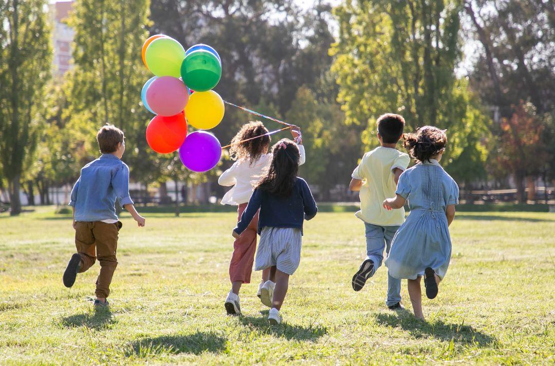 Children running in the park with balloons