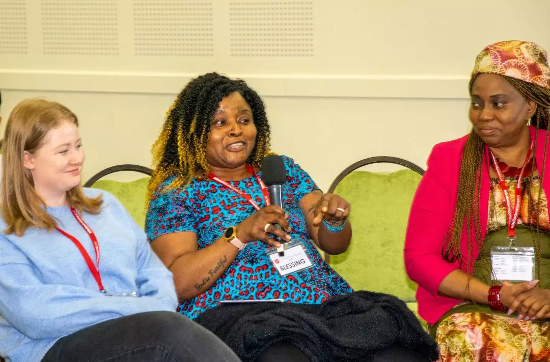 A photo of a delegate sharing with the conference from the audience holding a microphone