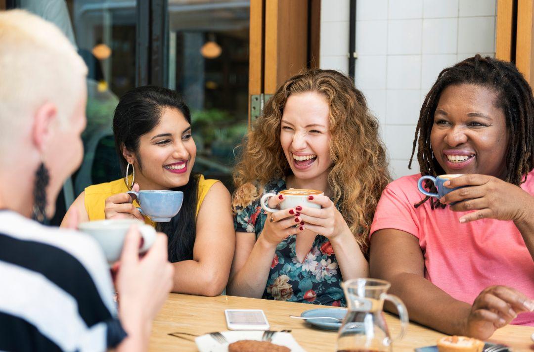 A photo of a diverse group of women drinking coffee and laughing