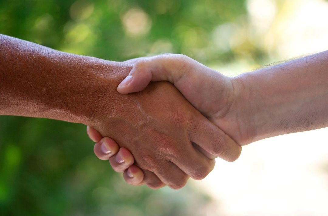 A photo of two people shaking hands outside