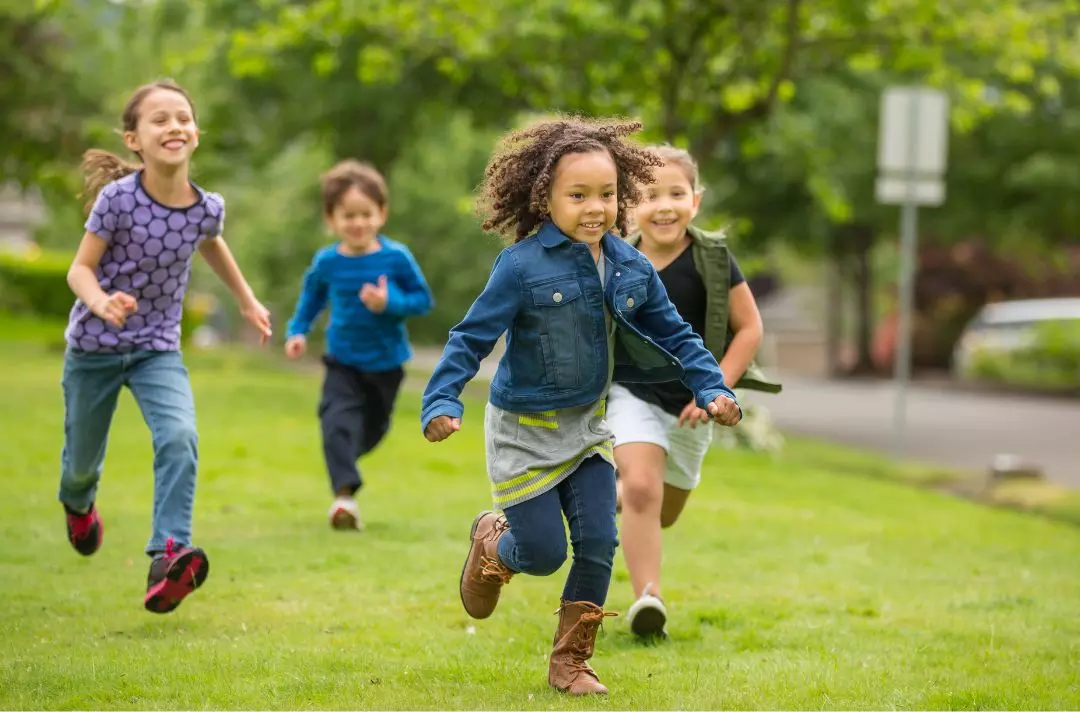 A photo of a group of children running through a park