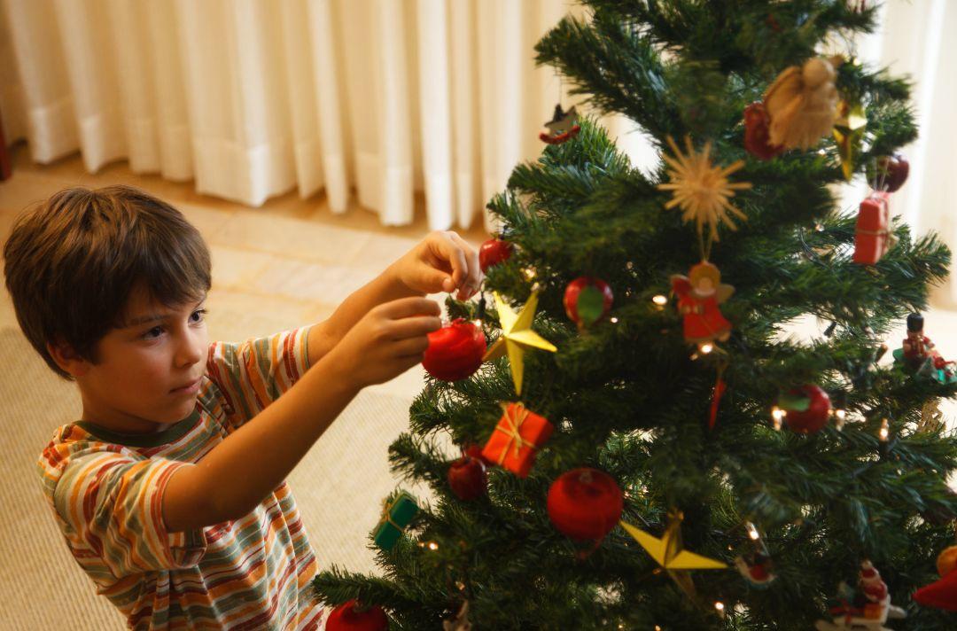 A photo of a child putting a bauble on a Christmas tree