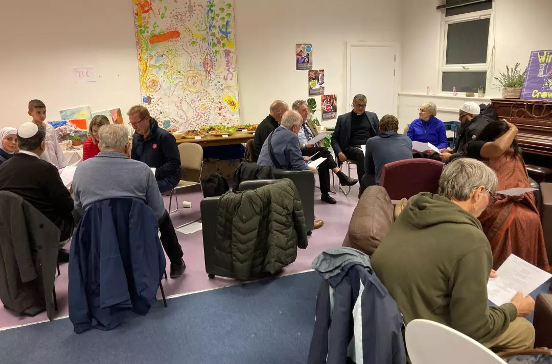 A photo of people from different faiths sitting in small groups talking