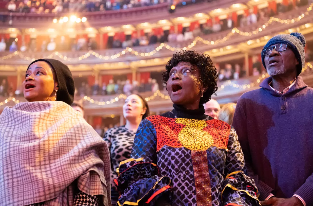 The photo is a close up of three members of the congregation, who are singing.