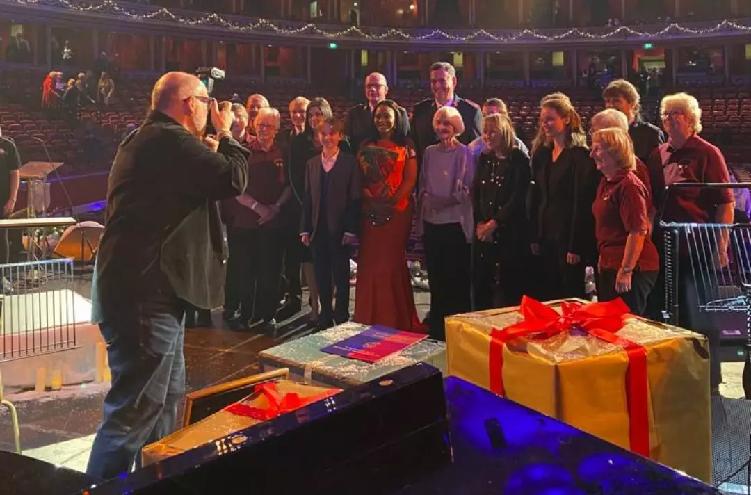 A photo of the performers posing for a group photo on stage at the end of the concert