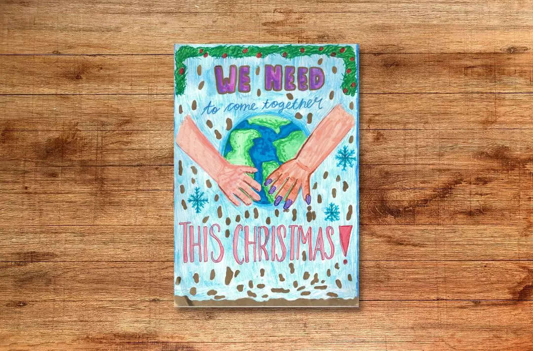 A Christmas card drawn by a child, featuring two hands holding the world, snow falling, and the text: 'We need to come together this Christmas!'