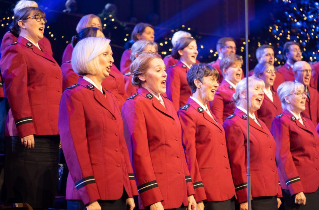 A photo of the International Staff Songsters singing at the Royal Albert Hall wearing red Salvation Army tunics
