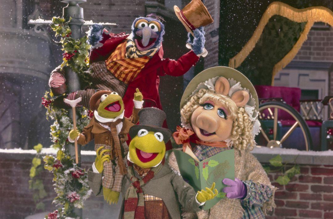 Muppet Christmas Carol promotional photo, featuring muppets, including Kermit the Frog, Miss Piggy and The Great Gonzo, dressed up in Victorian clothes and standing by a lampost in the snow