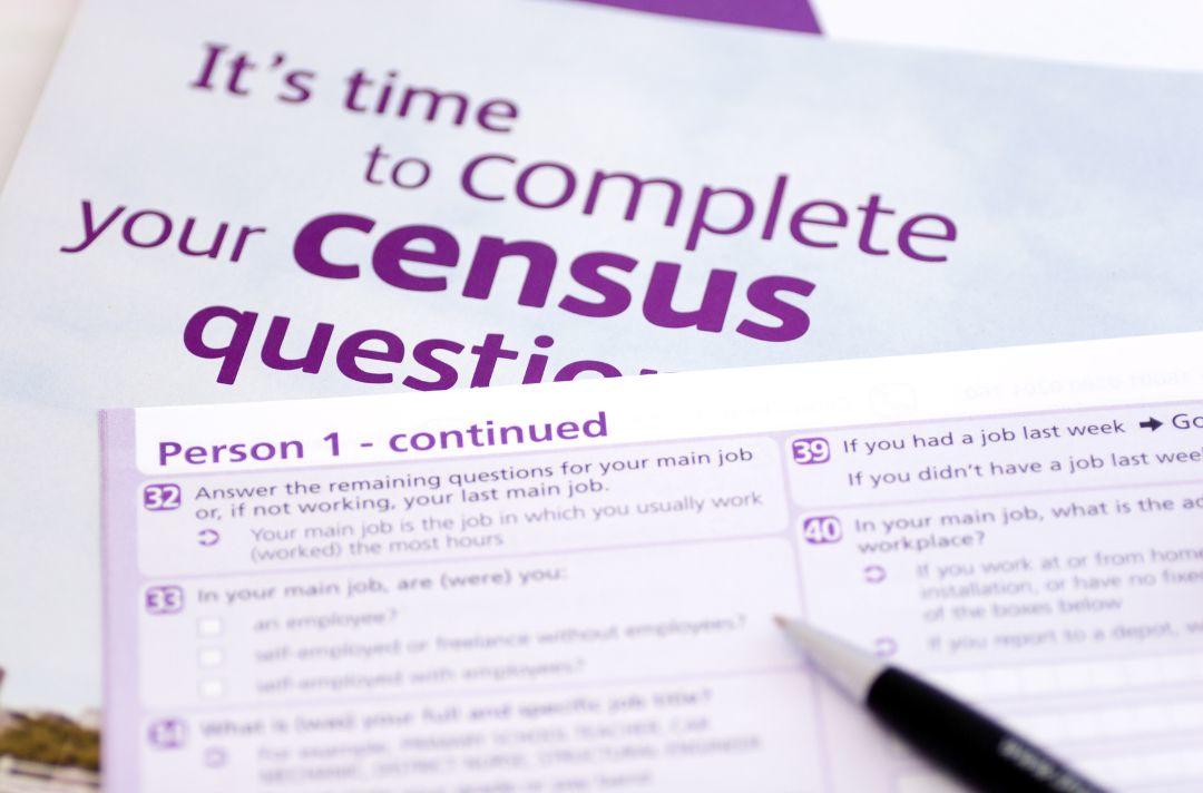 A photo shows a blank census form with a pen resting on the paper.