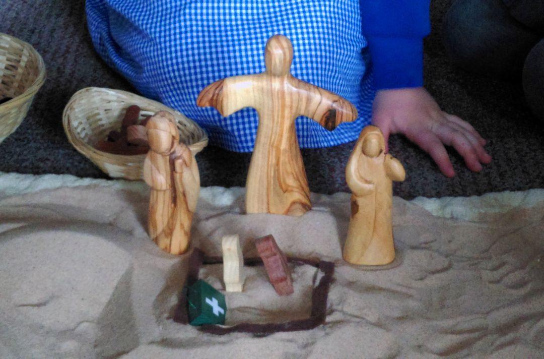 A photo of wooden Bible figures being played with by a girl in school uniform