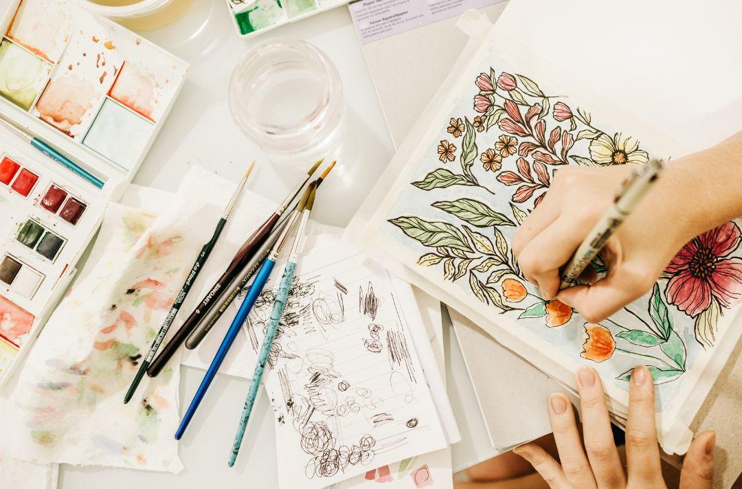 A photo of an artist using watercolours to paint a picture of flowers
