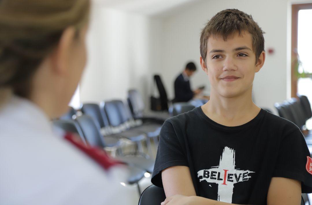 A photo of a teenage boy sitting talking to a Salvation Army officer