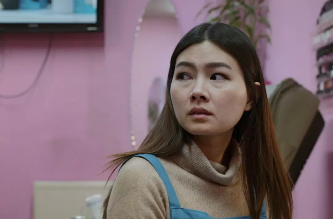 A photo of a victim of modern slavery working in a nail bar, looking anxious
