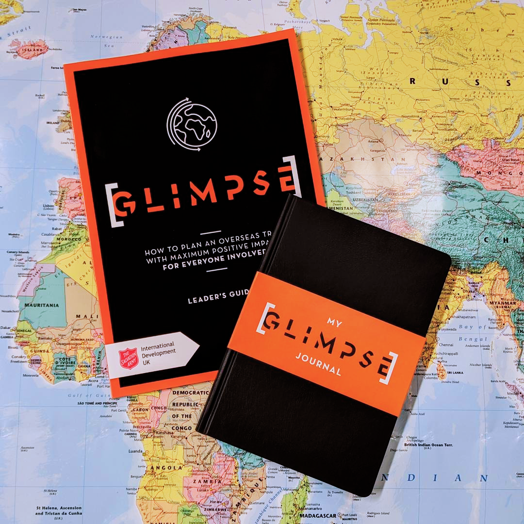 Photo of GLIMPSE Leader's Guide and Journal on top of a colourful map of the world