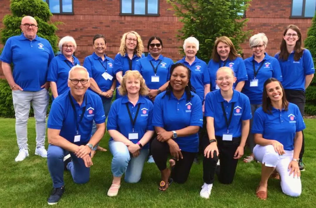 Image shows a group of smiling people in matching blue shirts.