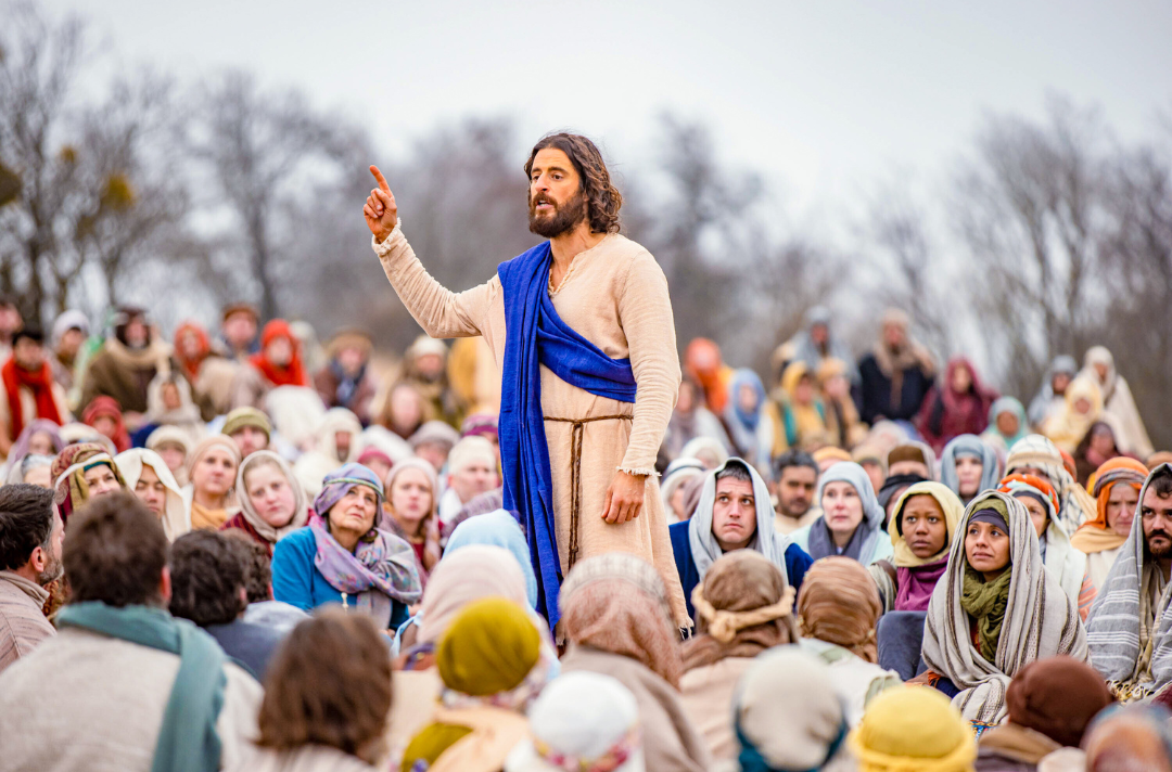 Photo shows Jesus speaking. He is surrounded by people who listen intently.‘The Chosen’ (2017 – present) | Courtesy of The Chosen