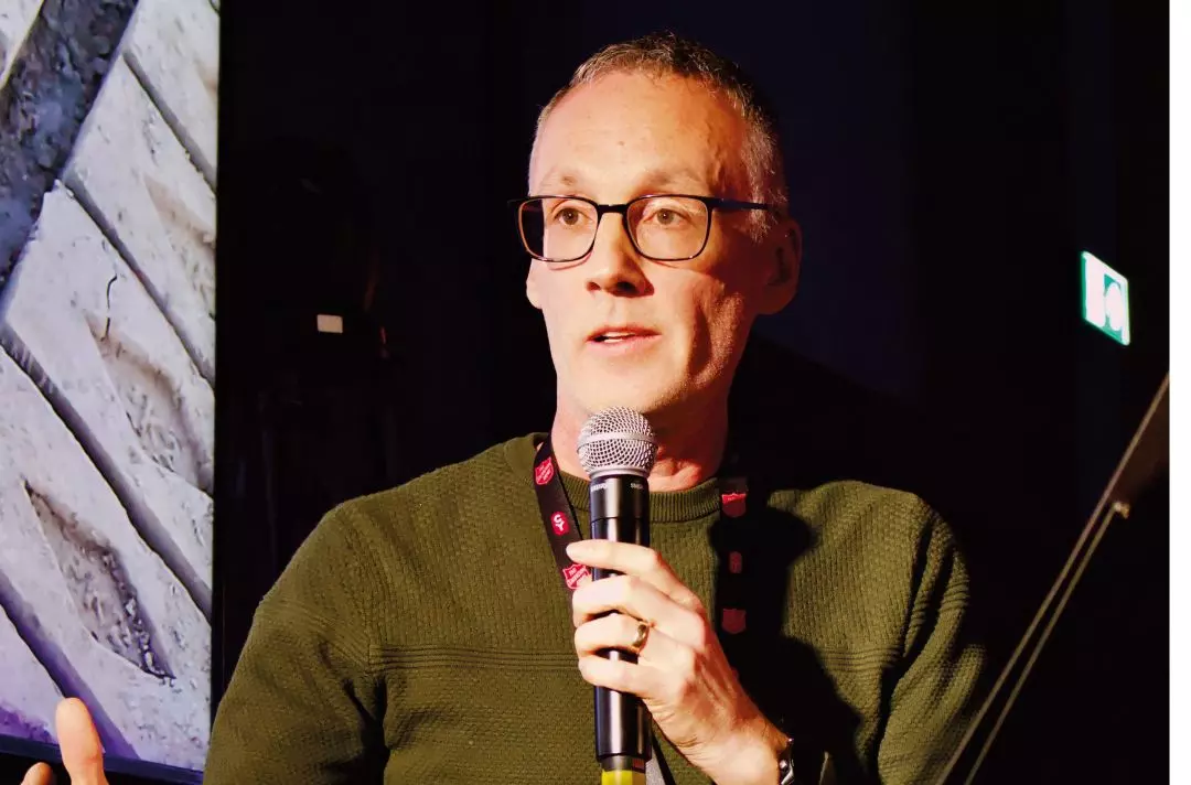 A photo of Andrew Grinnel speaking into a microphone at Shalom