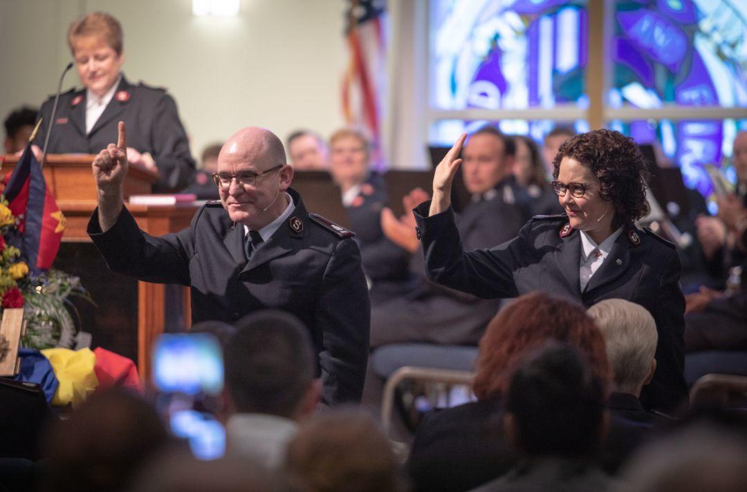 A photo of Lyndon and Bronwyn Buckingham in a Salvation Army meeting saluting the congregation