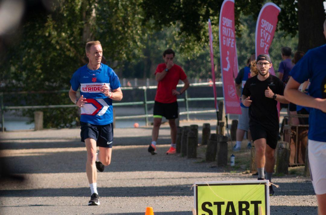 A photo of a man running in a Salvation Army running vest at Parkrun