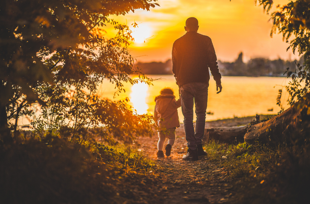 Photo shows a father and child walking down a path.