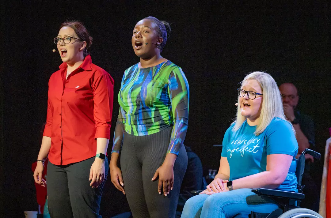 Photo shows three cast members of 'Belongings' singing ernestly.
